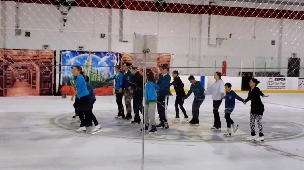 A figure skater on the ice with a volunteer