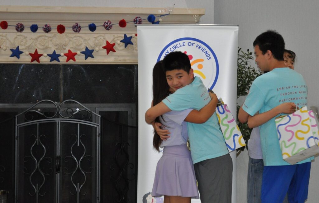 A My Circle of Friends volunteer sharing a hug at a community performance